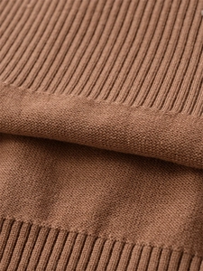 Detailed close-up of brown knit wool sweater texture showing rib and jersey stitch craftsmanship