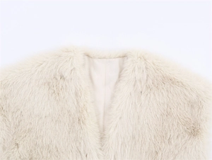 Detail of beige faux fur vest showing collarless design and smooth lining texture