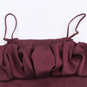 Détail d'un haut en satin bordeaux avec des plis texturés et des boucles dorées