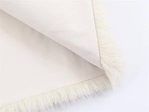 Detailed close-up of faux fur trim and twill fabric on the beige sleeveless vest