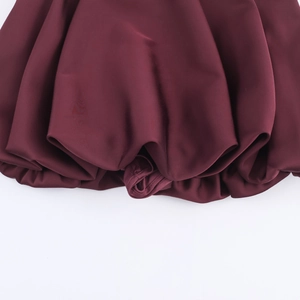 Détail de l'ourlet ballon en satin rouge foncé montrant la texture plissée et le tissu brillant