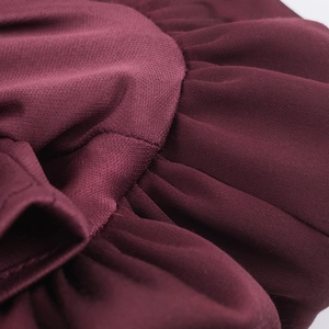 Détail macro d'un haut bordeaux montrant le tissu en maille plissée et les coutures texturées