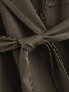 Détail d'une veste courte vert olive avec tissu en sergé et ceinture nouée à la taille