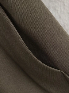 Gros plan du tissu sergé vert olive montrant les coutures de qualité sur le détail d'une poche