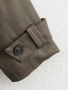 Détail macro des poignets en tissu sergé vert olive avec sangles boutonnées réglables