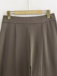 Détail du pantalon taille haute marron foncé avec plis frontaux et tissu fluide