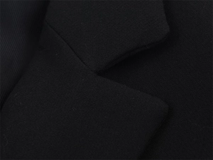 Close-up of black suit jacket lapel showing premium textured fabric and fine stitching