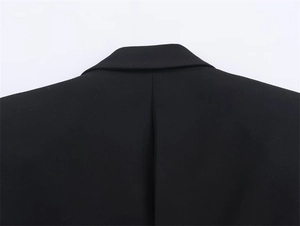 Detail of a black tailored blazer showing the neck seam and high-quality woven fabric