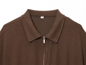 Detail of dark brown knit polo sweater featuring a metallic half-zipper and soft texture