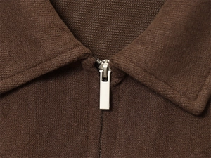 Detailed macro view of a brown knit top neckline featuring a sleek silver metal zipper