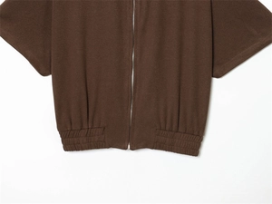 Detail of dark brown zip-up hoodie featuring silver metal zipper and ribbed cuffs