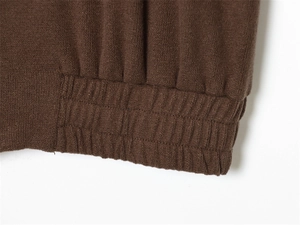 Macro shot of dark brown knit fabric showing the detailed double-ribbed hem and cuff texture