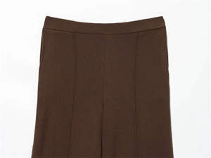 Detail of dark brown wide-leg trousers with vertical pleats and textured fabric