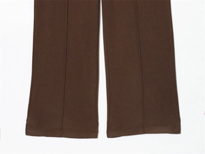 Detailed close-up of brown wide-leg trousers featuring a sharp vertical center seam