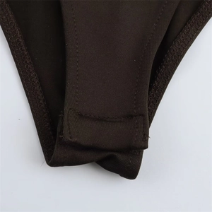Detail shot of the bottom snap-button closure on a brown long-sleeve knit bodysuit