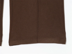 Close-up of dark brown knit fabric with fine vertical stitching and neat hem detail