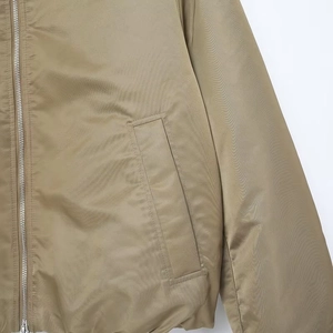 Detail of khaki bomber jacket featuring smooth silver zipper and fabric texture