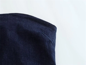 Close-up of the dark blue denim fabric texture and precise stitching on the dress edge