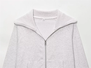 Detail of light gray zip-up sweatshirt showing metal zipper and fleece collar texture