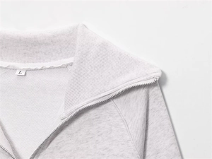 Detail of grey fleece sweatshirt featuring a ribbed lapel collar and silver metal zipper