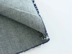 Macro view of raw frayed hem and stitching detail on blue denim strapless dress