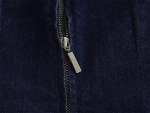 Detailed close-up of premium metal zipper on dark blue denim tube dress with fine texture