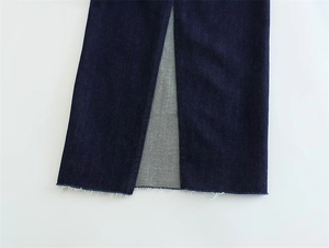 Detail of dark blue denim dress featuring frayed hem and a centered vertical front slit
