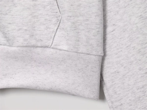 Detail of ribbed hem and kangaroo pocket seam on a grey heather fleece jacket