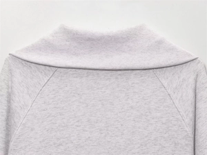 Detail of ribbed neckline and raglan sleeve stitching on light grey fleece jacket