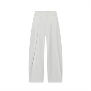Detail shot of the pleats and high-waist structure on white wide-leg trousers