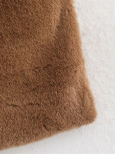 Dettaglio della morbida pelliccia sintetica marrone e del tessuto peluche del gilet