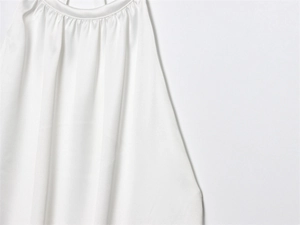 Detalle de top de satén blanco con cuello halter redondo y textura plisada suave