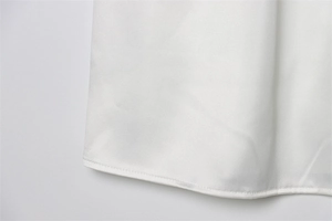 Primer plano macro de costuras precisas y dobladillo curvo en un top halter blanco