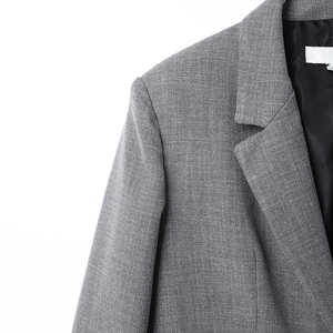 Detalle de chaqueta gris de espiga con costura en hombro y forro de seda negra suave