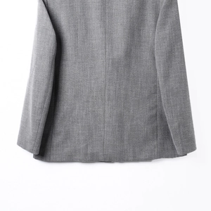 Primer plano detallado del dobladillo de la chaqueta gris con textura de espiguilla