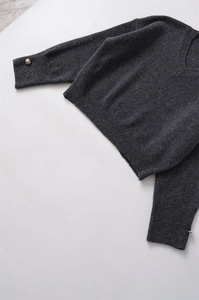 Détail du pull en maille gris foncé avec poignets côtelés et boutons en métal argenté