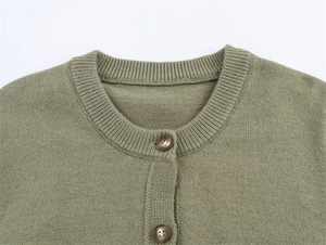 Detail of olive green knit cardigan featuring round neck and ribbed texture button placket
