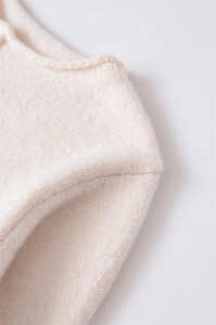 Macro dettaglio del colletto di un maglione a coste color crema con cuciture fini