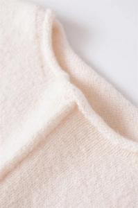 Dettaglio ravvicinato della trama in maglia a coste crema con cuciture rifinite