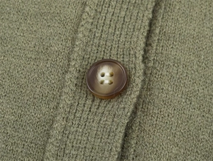 Detailed close-up of dark marble button on olive green knit cardigan fabric