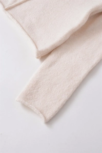 Dettaglio ravvicinato del maglione in maglia crema con texture morbida e bordi a coste