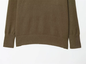 Close-up of olive green knit sweater showing ribbed hem and cuff texture detail