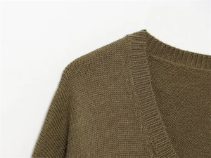 Detail of V-neck ribbed neckline and shoulder seams on olive green knit sweater