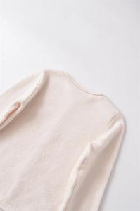 Dettaglio del maglione in maglia a coste beige con scollo rotondo e trama morbida