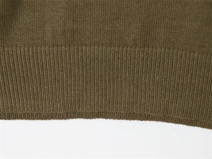 Detailed macro view showing the ribbed hem and olive green knit texture of the sweater