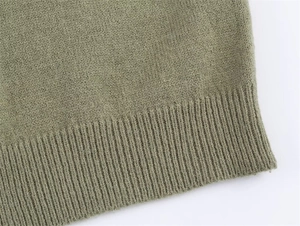 Detailed view of the soft green knit top featuring premium ribbed hem and fine texture