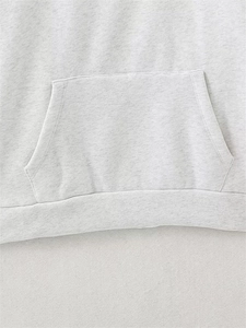 Detail view of light grey hoodie featuring high-quality kangaroo pocket and ribbed hem