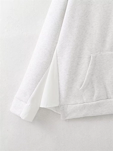 Detail of light grey hoodie featuring unique side split with white fabric contrast panel