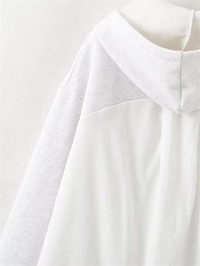 Close-up of minimalist hoodie featuring light grey knit and white fabric patchwork design