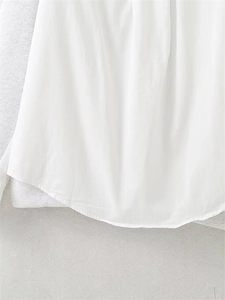 Detail of curved hemline on a minimalist white hoodie with clean stitching and soft fabric